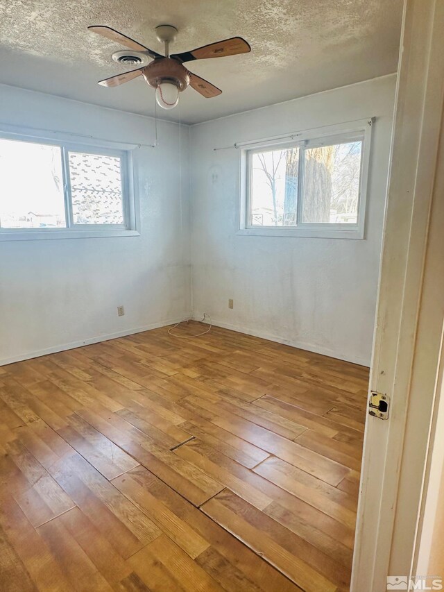 815 16th St, Lovelock, NV 89419 - empty room with hardwood / wood-style floors, a ceiling fan, healthy amount of natural light, and a textured ceiling