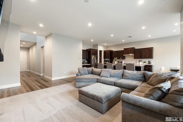 living area with light wood-style flooring, recessed lighting, and baseboards