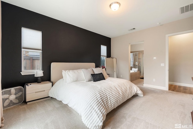 bedroom featuring light colored carpet, baseboards, and ensuite bathroom