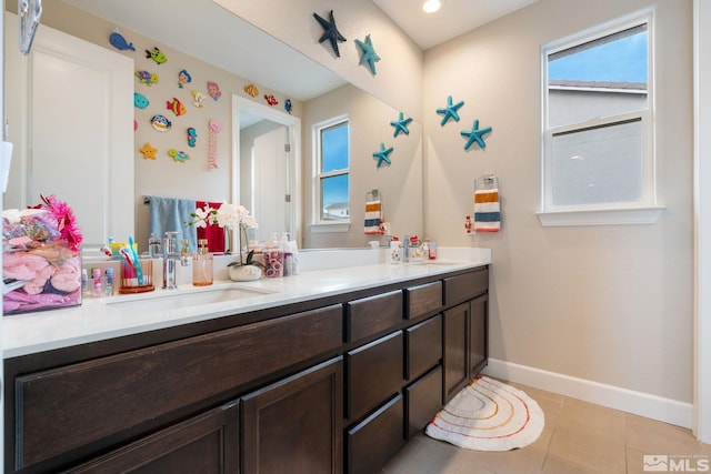 bathroom featuring baseboards, double vanity, plenty of natural light, and tile patterned floors