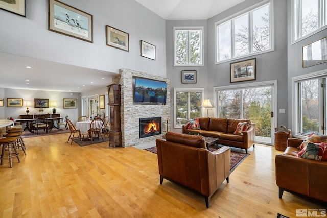 6350 Green Ranch Rd, Reno, NV 89519 - living room featuring a towering ceiling, a stone fireplace, light wood-style floors, and plenty of natural light