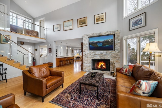 6350 Green Ranch Rd, Reno, NV 89519 - living area featuring high vaulted ceiling, light wood-type flooring, a stone fireplace, stairs, and baseboards