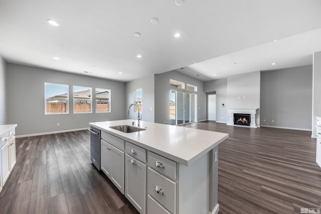 kitchen with a sink, light countertops, a center island with sink, dark wood-style floors, and recessed lighting