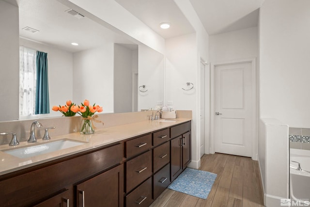 11223 Freedom Range Ln, Reno, NV 89521 - bathroom with double vanity, a tub to relax in, and wood finished floors