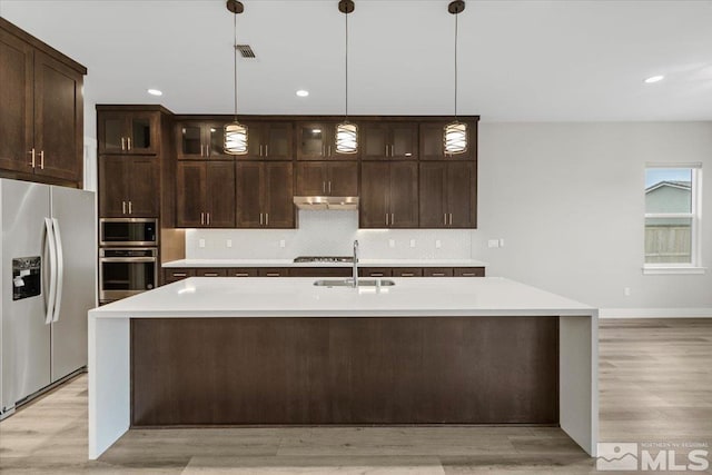 kitchen with appliances with stainless steel finishes, a sink, light countertops, light wood-style floors, and recessed lighting