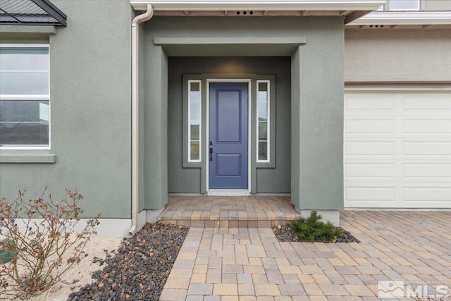 entrance to property with stucco siding and a garage