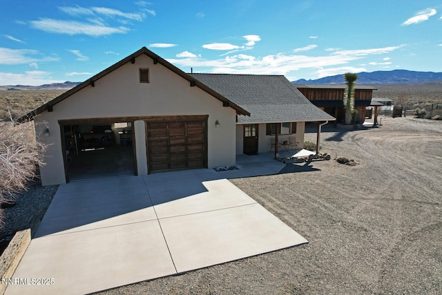 10 Dee Ct, Smith Valley, NV 89444 - view of front of house featuring a mountain view, a porch, stucco siding, driveway, and an attached garage