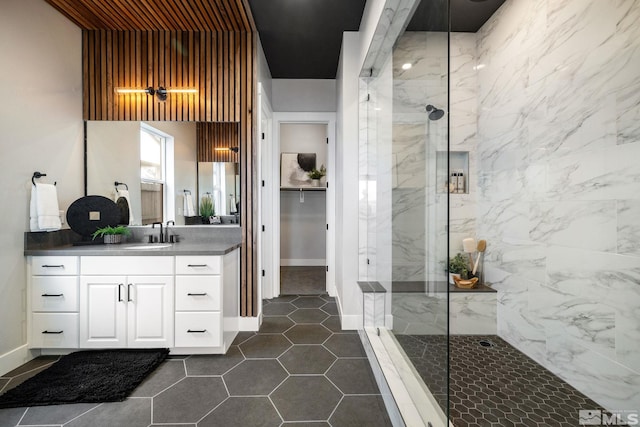 full bathroom featuring a marble finish shower, vanity, baseboards, and tile patterned floors