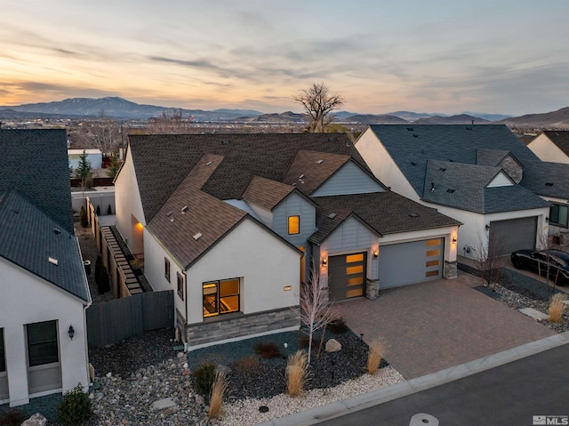 view of front of home with a garage, stone siding, a mountain view, driveway, and stucco siding