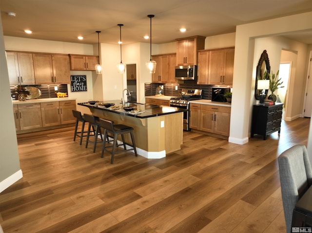 kitchen with appliances with stainless steel finishes, decorative backsplash, a breakfast bar area, recessed lighting, and hanging light fixtures