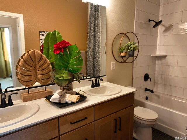 full bathroom featuring double vanity, toilet, shower / bath combination with curtain, and a textured wall