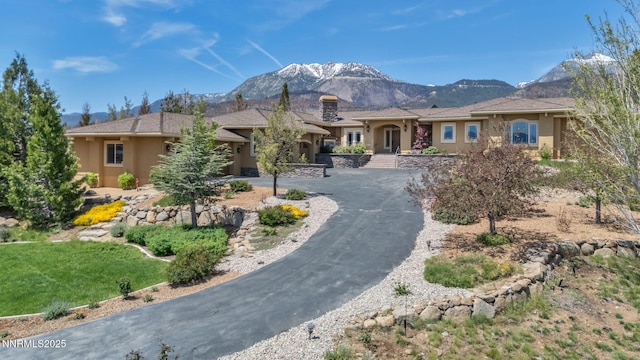 227 S Earlham, Reno, NV 89511 - view of front of home featuring stucco siding, a mountain view, curved driveway, and a chimney
