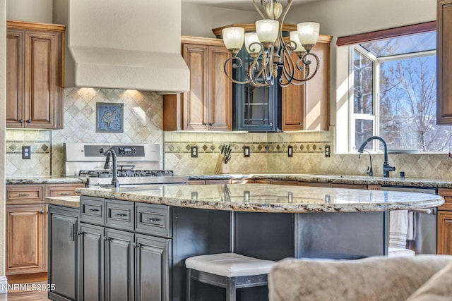 227 S Earlham, Reno, NV 89511 - kitchen featuring appliances with stainless steel finishes, an island with sink, custom range hood, a chandelier, and light stone countertops