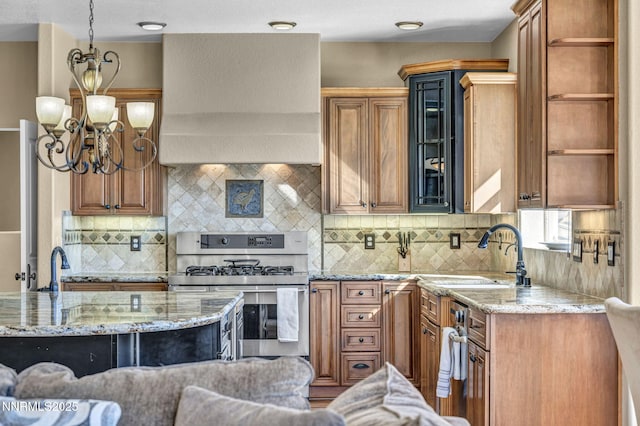 227 S Earlham, Reno, NV 89511 - kitchen with stainless steel gas stove, custom exhaust hood, a sink, a chandelier, and light stone counters