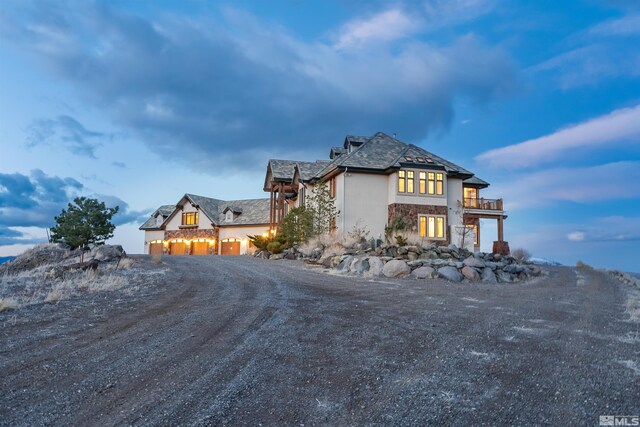 525 Cable Canyon Way, Fernley, NV 89408 - view of side of home with a balcony, stone siding, stucco siding, and dirt driveway