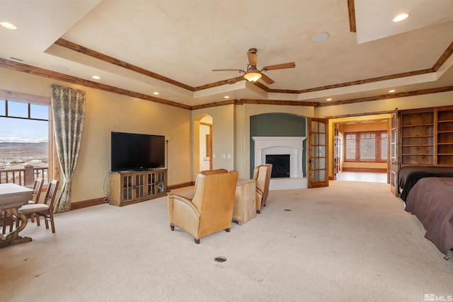 525 Cable Canyon Way, Fernley, NV 89408 - carpeted living room featuring a tray ceiling, ornamental molding, baseboards, arched walkways, and a ceiling fan