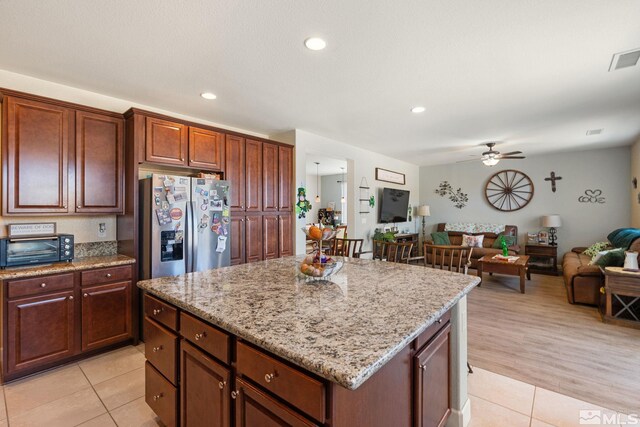 2780 Tobiano Dr, Reno, NV 89521 - kitchen with stainless steel refrigerator with ice dispenser, light tile patterned floors, a ceiling fan, a center island, and light stone counters