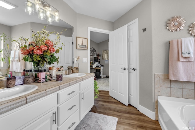 953 Julia Ln, Fernley, NV 89408 - bathroom featuring wood finished floors, double vanity, a bath, and baseboards
