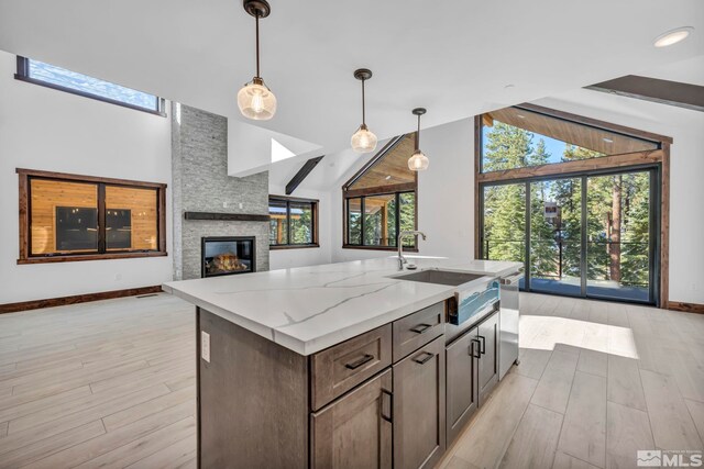kitchen featuring open floor plan, plenty of natural light, pendant lighting, high vaulted ceiling, and light wood-type flooring