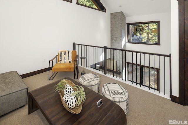 living area with carpet floors, vaulted ceiling, and baseboards