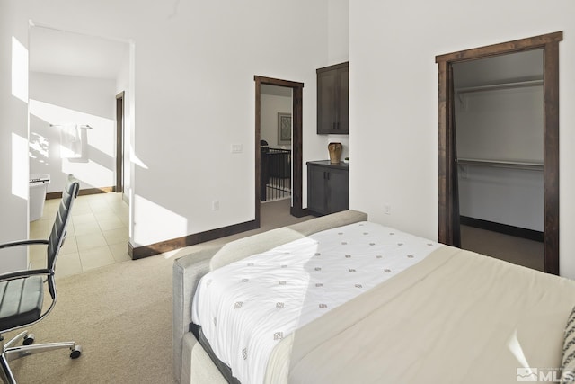 bedroom with light carpet, a spacious closet, a closet, and light tile patterned flooring