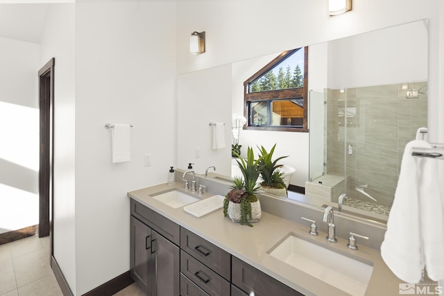 full bath featuring a stall shower, double vanity, tile patterned floors, and baseboards