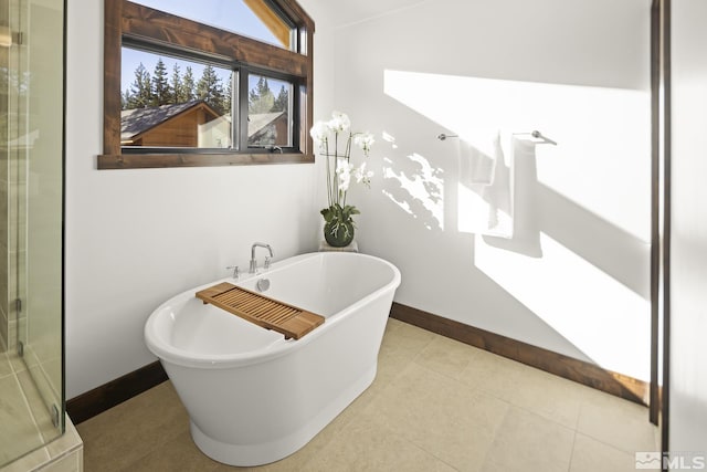 bathroom featuring a freestanding tub, baseboards, a shower with shower door, and tile patterned floors