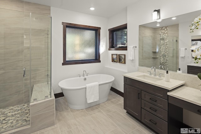 bathroom featuring a shower stall, baseboards, a soaking tub, vanity, and recessed lighting