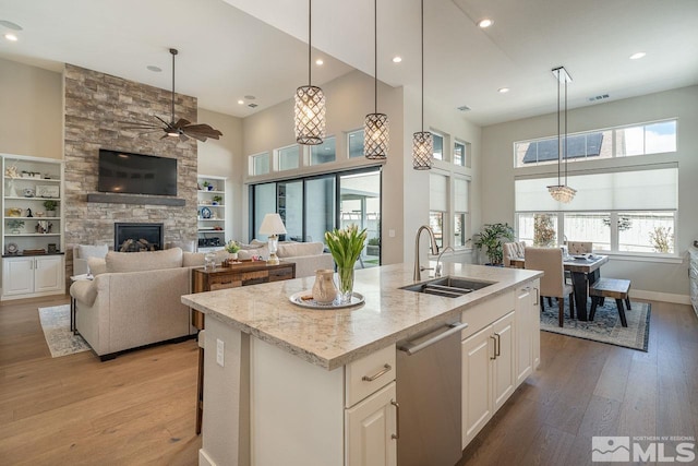 721 Marewood Trl, Reno, NV 89511 - kitchen with a sink, a ceiling fan, stainless steel dishwasher, a stone fireplace, and light wood-style flooring