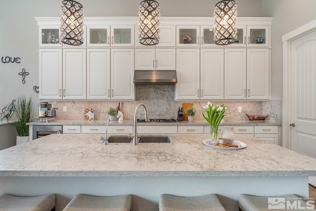 721 Marewood Trl, Reno, NV 89511 - kitchen with a sink, a breakfast bar, under cabinet range hood, and tasteful backsplash