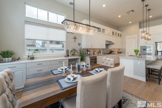 721 Marewood Trl, Reno, NV 89511 - dining area with a chandelier, a towering ceiling, recessed lighting, wood finished floors, and wine cooler