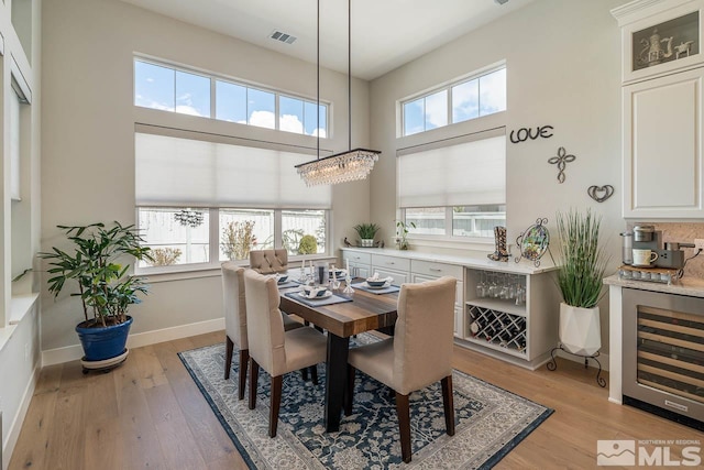 721 Marewood Trl, Reno, NV 89511 - dining area with wine cooler, light wood finished floors, baseboards, and a towering ceiling