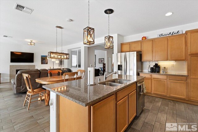 9820 Hafflinger Ln, Reno, NV 89521 - kitchen with stainless steel appliances, a sink, wood finished floors, a kitchen island with sink, and recessed lighting