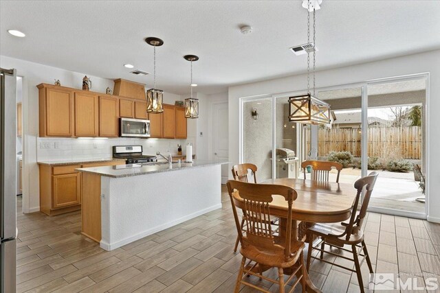 9820 Hafflinger Ln, Reno, NV 89521 - kitchen featuring stainless steel appliances, decorative backsplash, recessed lighting, light wood-style flooring, and decorative light fixtures