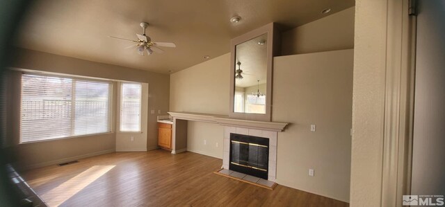 933 Julia Ln, Fernley, NV 89408 - unfurnished living room featuring a ceiling fan, lofted ceiling, a fireplace, wood finished floors, and healthy amount of natural light