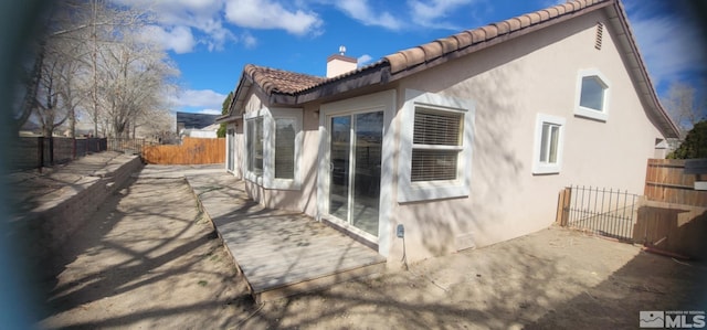 933 Julia Ln, Fernley, NV 89408 - back of house with stucco siding, a tile roof, a chimney, fence, and a patio
