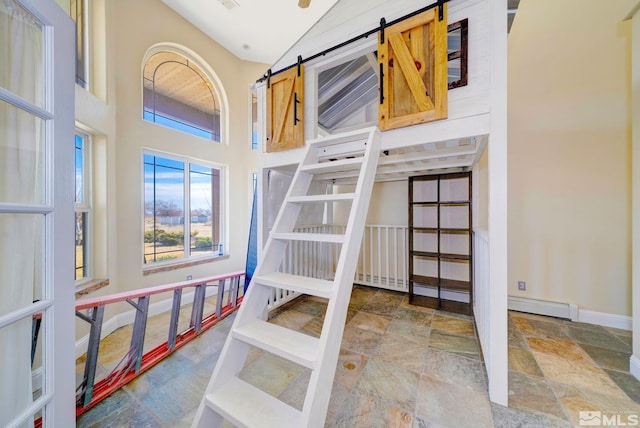 1253 Briggs Ln, Fallon, NV 89406 - unfurnished bedroom featuring a barn door, baseboards, stone finish floors, and a towering ceiling