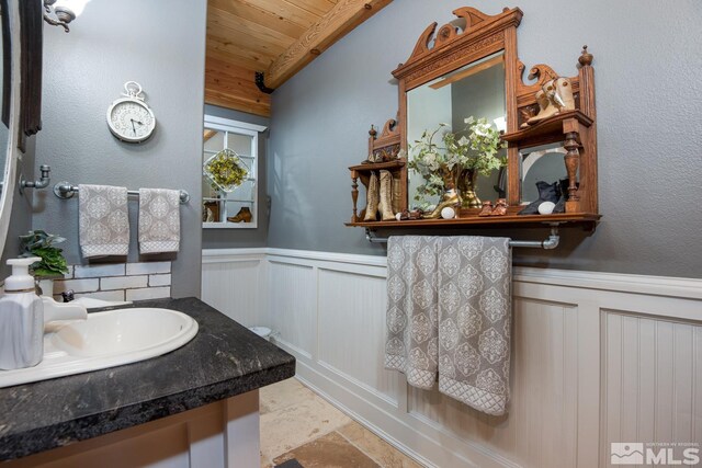 1101 Sierra Country Ct, Gardnerville, NV 89460 - bathroom featuring wood ceiling, a wainscoted wall, stone finish floors, a decorative wall, and vanity