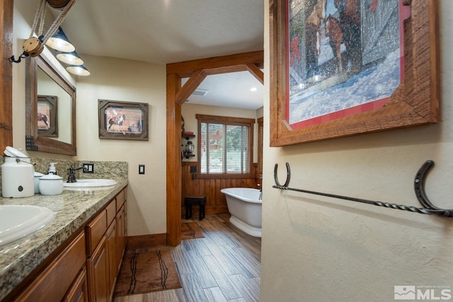 1101 Sierra Country Ct, Gardnerville, NV 89460 - bathroom featuring wood finished floors, a freestanding bath, double vanity, and baseboards