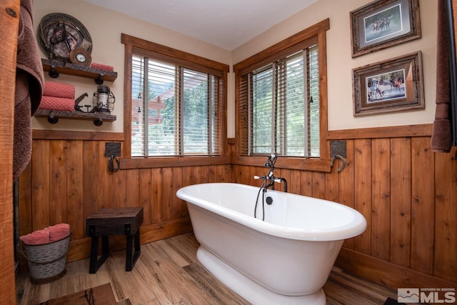 1101 Sierra Country Ct, Gardnerville, NV 89460 - bathroom featuring a wainscoted wall, wood finished floors, a freestanding tub, and wooden walls