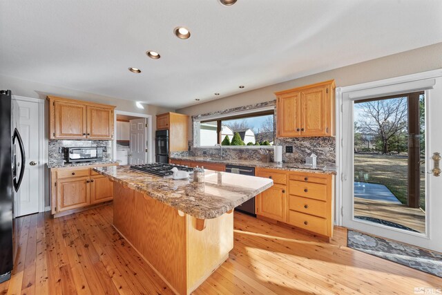 1973 Arabian Ln, Gardnerville, NV 89410 - kitchen with black appliances, a kitchen island, decorative backsplash, a sink, and light wood-type flooring