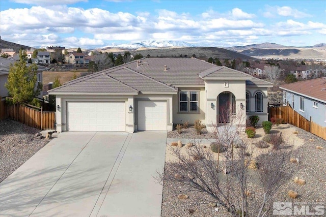 6141 Solstice Dr, Sparks, NV 89436 - mediterranean / spanish house with a mountain view, a garage, fence, driveway, and stucco siding