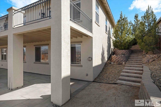 6141 Solstice Dr, Sparks, NV 89436 - view of home's exterior featuring stucco siding, a balcony, a patio area, and stairs