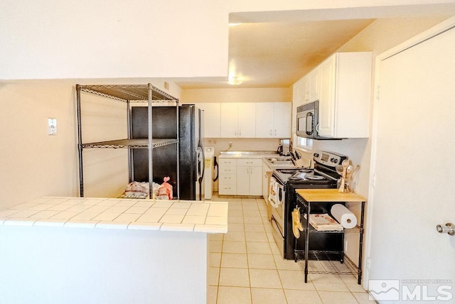 1845 Auburn Way, Reno, NV 89502 - kitchen featuring electric range, tile countertops, black microwave, light tile patterned floors, and white cabinetry
