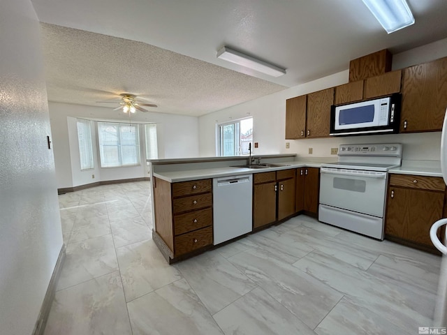 kitchen featuring white appliances, light marble finish floors, a sink, a peninsula, and light countertops