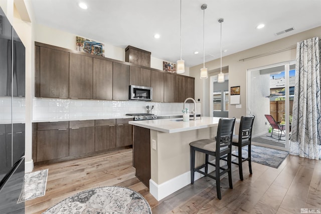 7317 Oakmont Ln, Sparks, NV 89436 - kitchen with stainless steel microwave, light wood finished floors, a sink, tasteful backsplash, and light countertops