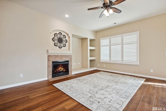 823 Gullane Ct, Dayton, NV 89403 - living room featuring ceiling fan, a tile fireplace, dark wood-style floors, built in features, and baseboards