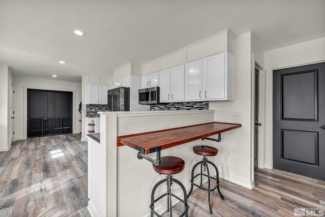 285 James Ave, Dayton, NV 89403 - kitchen featuring stainless steel appliances, baseboards, white cabinetry, light wood-type flooring, and a breakfast bar