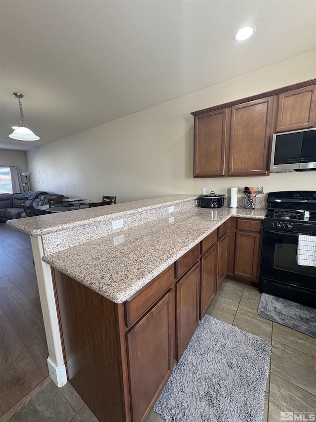 5282 Western Way, Winnemucca, NV 89445 - kitchen with stainless steel microwave, black range with gas cooktop, a peninsula, light stone countertops, and open floor plan