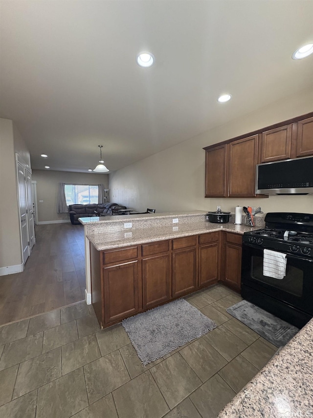 5282 Western Way, Winnemucca, NV 89445 - kitchen featuring black gas stove, stainless steel microwave, a peninsula, open floor plan, and light stone countertops